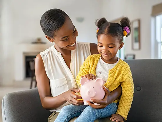 Image of mother holding a child with a piggy bank