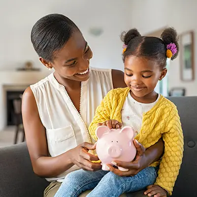 Image of mother holding child with piggy bank