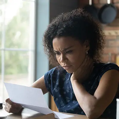 Image of woman with a worried look starting at a bill