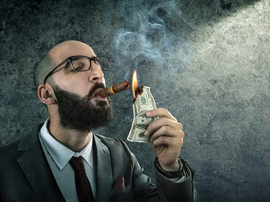 Image of man lighting cigar with cash