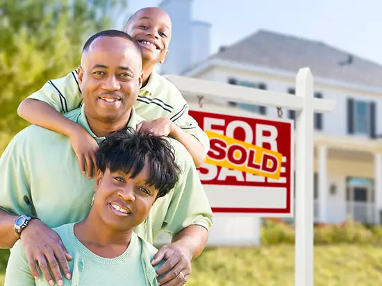 Image of family in front of SOLD real estate sign