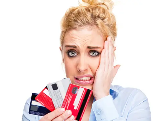 Image of woman holding many credit cards looking worried