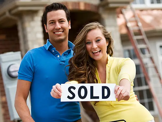 Image of couple holding SOLD sign