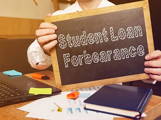 Image of person holding sign labeled STUDENT LOAN FOREBEARANCE